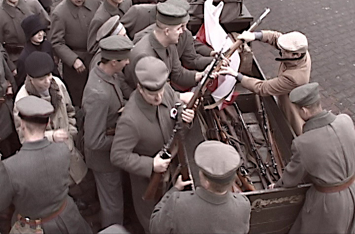 Kadr filmu o Powstaniu Wielkopolskim, grupa ludzi rozdziela broń